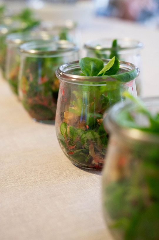 Gläser mit gesunden Salatsnacks stehen in einer Reihe auf einem Tisch.