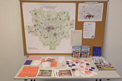 Ein Karte von Dortmund im Großformat, auf der die einzelnen Kioskstandorte mit Pins markiert sind. Davor ein Tisch mit Aufklebern, Broschüren und Bildbänden zum Thema.