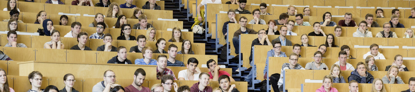Eine Dozierende steht vor Studierenden in der Vorlesung im Hörsaal. 